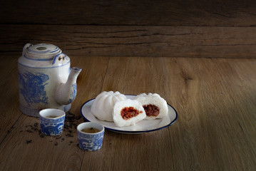 Steam stuff Buns (Sa La Pao) Stuffed red pork chop Chinese snack with Chinese pot tea in dim light on wooden background
