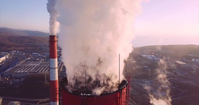 Panoramic close view of Central Heating and Power Plant chimney top with steam rising from it. Two more chimneys are on the background. Vladivostok, Russia. Sunrise. Aerial