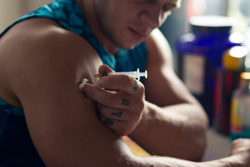 Strong bodybuilder making an injection