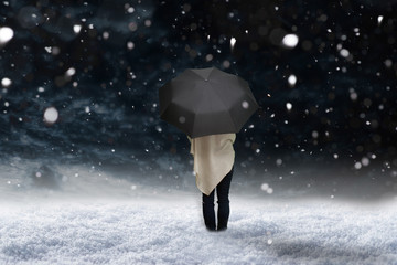 Frau steht mit Regenschirm im Schnee