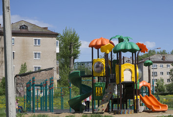 A children's playground, a slider located on the sand.