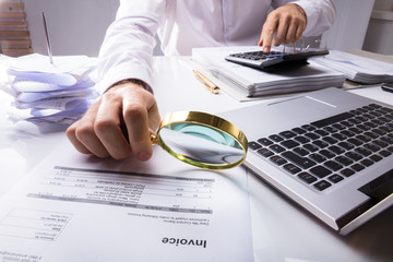 Auditor Checking Invoice Using Magnifying Glass
