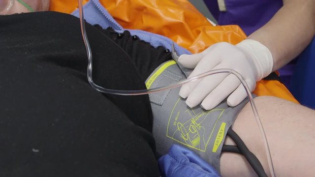 Emergency medical service. Female EMS paramedic treating elderly patient in ambulance during transport. Close-up