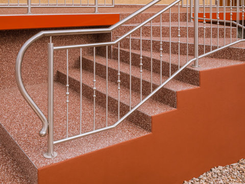 Modernes Treppengel&auml;nder aus Edelstahl an Au&szlig;entreppe mit Steinteppich in rotbraun - Modern stainless steel railing on outside staircase with stone carpet in red-brown 