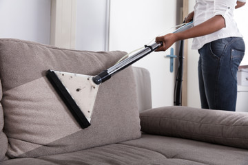 Housewife Cleaning Sofa With Vacuum Cleaner