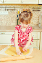 Obraz premium Cute little girl helping her mother bake cookies in a kitchen.
