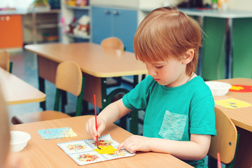 Cute little boy engaged in art and craft in classroom . Learning and education concept.