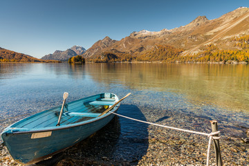 blue rowboat on the shore of a mountain lake in the Engadin near St. Moritz on a gorgeous fall day