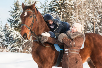 Small girl and mom near horse in a winter