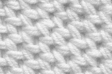 Knitting from woolen threads with a large pattern. The texture of the fibers is white.