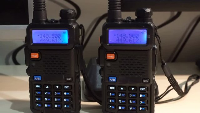 Two black handled portable walkie- talkie radio transmitter working and flashing in the dark