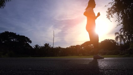 Asian woman silhouette is jogging in evening park.