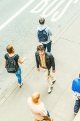 European guy traveling in New York, wearing black jacket, yellow pants, passing by strangers, walking on sidewalk on street, looking for you. Top View. concept of lonely man looking for friendship..