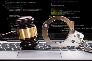 Handcuffs And Gavel In Front Of Laptop Screen