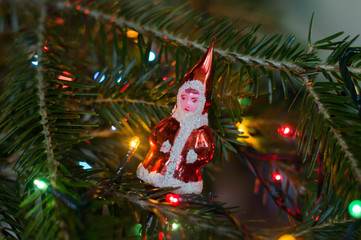 Old santa claus glass figurine  with soft focus on blurry bokeh christmas tree background