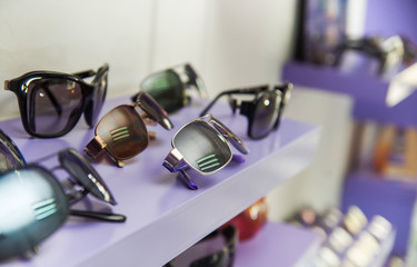 Obraz na płótnie Canvas Close up of assorted beautiful glasses in optician store inside of purple showcase, in a blurred background