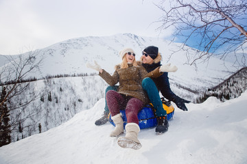 Happy people on tube outdoors in mountains in winter snow. Concept of Christmas holidays