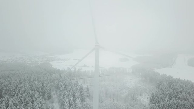 Aerial view of a snowy winter landscape with wind turbines
