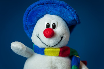 A cute little soft snowman with a blue hat and a colorful scarf