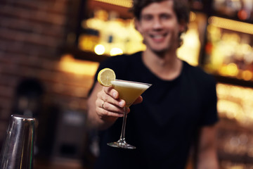 Handsome bartender serving cocktails in a pub