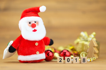 Santa claus doll with 2018 wooden cube block and christmas props decorations  against wood background.