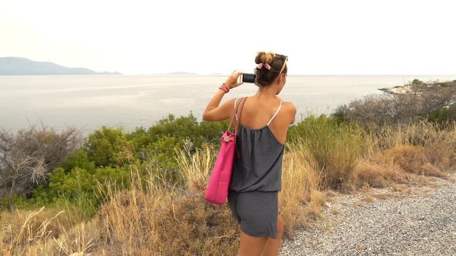 Woman taking photo while hiking on island, super slow motion 240fps
