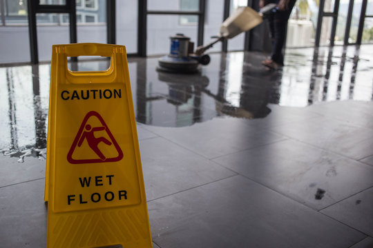 The People Cleaning Floor With Machine.