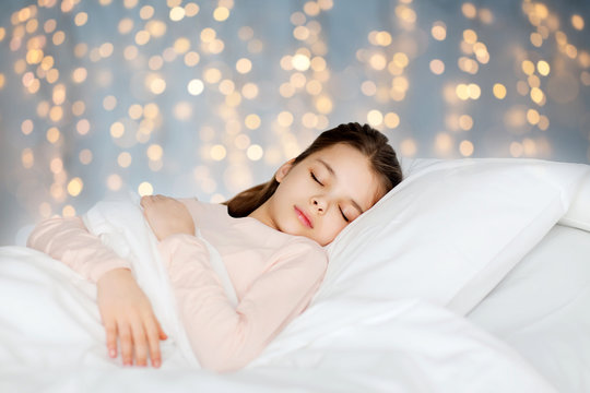 girl sleeping in bed over holidays lights