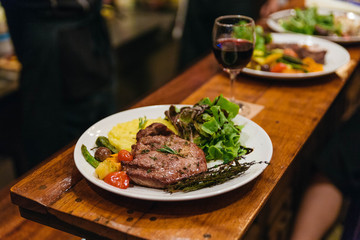 Stir fried pork steak served with vegetable side dish, salad and mash potato topping with balsamic dressing and red wine.