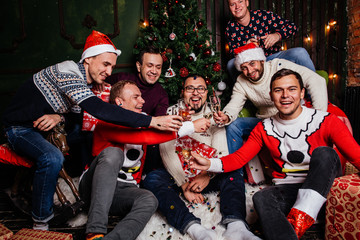 Friends celebrating Christmas with champagne glasses and make a wish while sitting near Christmas tree