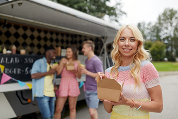 happy woman with wok and friends at food truck
