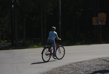 Side view portrait of a young beautiful woman riding on bicycle in city street