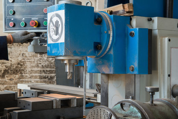 drilling machine. a factory worker operates a woodworking machine