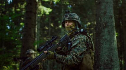 Fototapeta premium Fully Equipped Sniper Soldier Wearing Camouflage Uniform Attacking Enemy, Rifle in Firing Position. Military Operation in Action, Squad Running in Formation Through Dense Forest. Side View Long Shot.