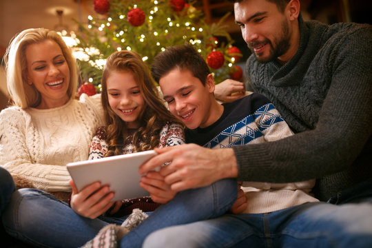 Family together for Christmas looking photos on tablet