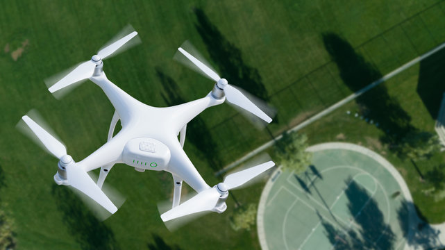Unmanned Aircraft System (UAV) Quadcopter Drone In The Air Over A Park.