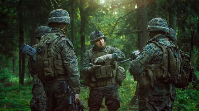 Squad Leader Discusses Military Operation Details with Soldiers, Commander Gives Orders. Fully Equipped and Armed Soldiers Ready for Mission in a Dense Forest.