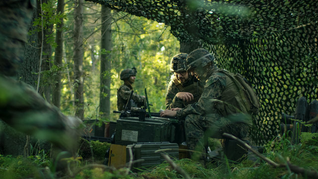 Military Staging Base, Officer Gives Orders to Signalman, They Use Radio and Army Grade Laptop. They're in Camouflaged Tent in a Forest. They're on Reconnaissance Operation/ Mission.