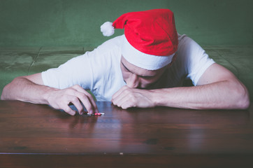 Young man with Santa Claus hat suffering from suicidal depression feeling lonely and sad for New Year and Christmas holiday suicide concept