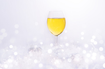 Wineglass of white wine on a white blurred background. Blurred bokeh light background, Christmas and New Year holidays background