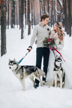 Cute couple with two siberian husky are posed on background of snowy forest. Winter wedding. Artwork