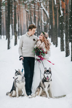 Cute couple with two siberian husky are posed on background of snowy forest. Winter wedding. Artwork