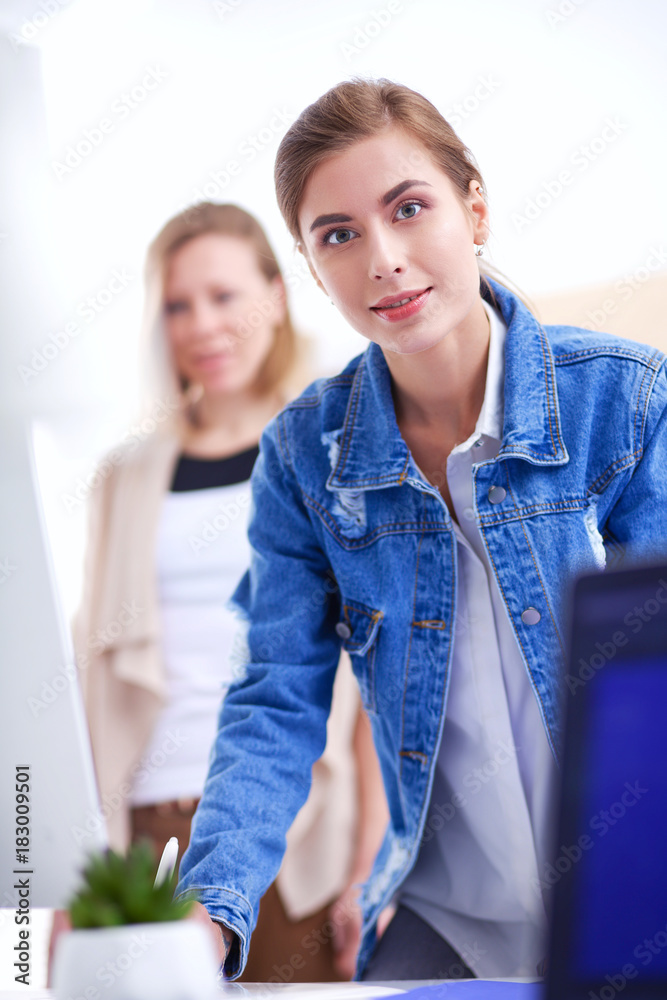 Wall mural two young woman standing near desk with instruments, plan and laptop.