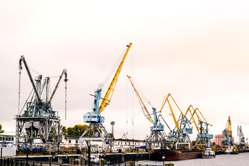 A river port with cranes and docks early in the morning. Deserted port on a cloudy day at dawn