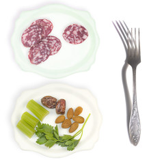 A dish of vegetarian food and the dish with slices of sausage next to the fork on white background