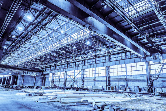 Unified standard typical span prefabricated of a steel frame production building. Industrial metalwork production hall with overhead cranes. Background in blue tone
