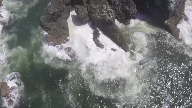 Aerial of water crashing on rocks