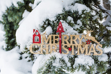 Merry Christmas Wooden Sign Hanging on a Snowy  Pine Tree .Christmas Card
