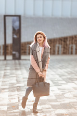 Beautiful fashion girl walk on the street with bag and smile to camera