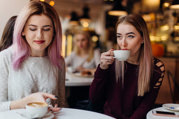 Two girls meat at coffee place and talk to each other, make conversation